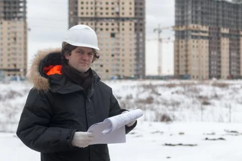 Worker or engineer holding drawing in hands and reading it on background of new Stock Photos