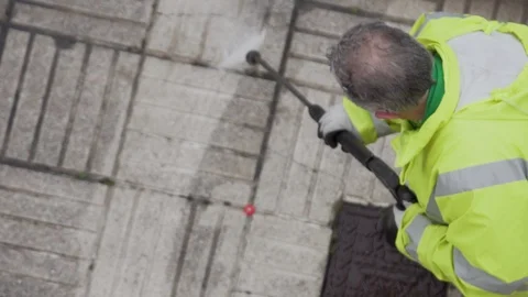 Worker or sweeper cleaning a sidewalk with pressurized water Video stock 128809615