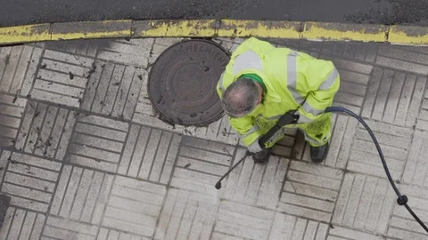 Worker or sweeper cleaning a sidewalk with pressurized water Видео 128809753