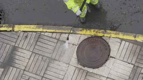 Worker or sweeper cleaning a sidewalk with pressurized water Видео 128809781