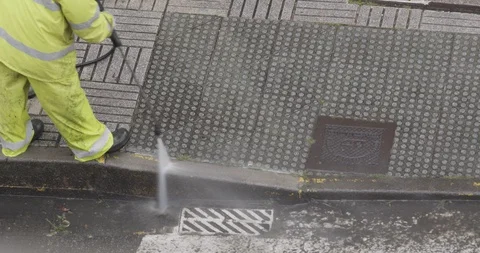 Worker or sweeper cleaning a sidewalk with pressurized water Vidéo 129453413
