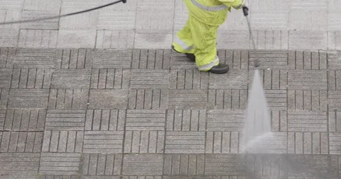 Worker or sweeper cleaning a sidewalk with pressurized water Stock-Footage 129453418