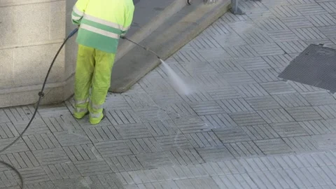 Worker or sweeper cleaning a sidewalk with pressurized water Video stock 151115033
