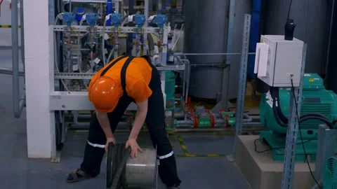 A worker in an orange helmet winds up a rubber hose from a breathing apparatus Stock Footage 168535621