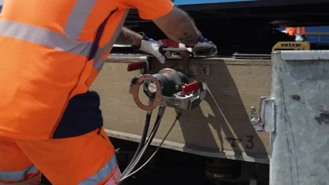 Worker in Orange PPE Tightening Cable Clamps on Railway Wagon Stock Footage 337799503
