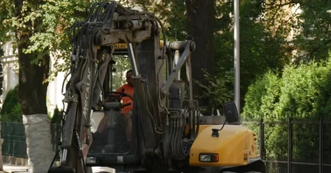 Worker in Orange Workwear Have Got Out Of Yellow Excavator Road Repair Paving Stock Footage 54334937