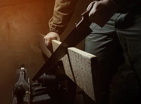 Worker in outfit with blue gloves using handsaw. Foto stock