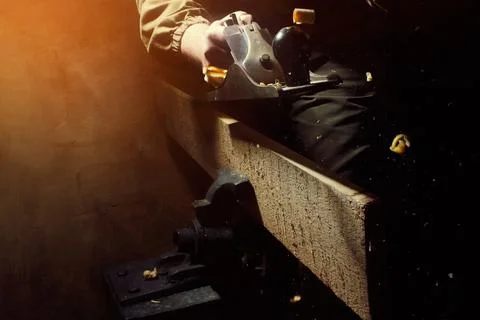 Worker in outfit with blue gloves using hand plane tool. Stock Photos