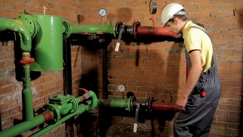 A worker in overalls opens the water valve. The man includes heating in the 動画素材 76259313