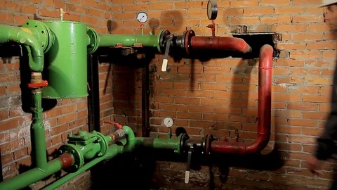 A worker in overalls opens the water valve. plumber comes and opens the valve Stock Footage 77123349