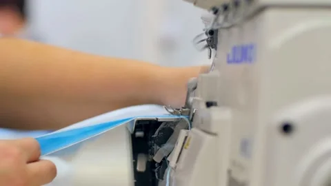 Worker overlocks stitch of disposable uniform at plant Video stock 147153852