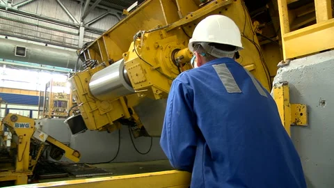 Worker oversees the work of the metal rolling machine Stock Footage 98108532