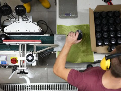 Worker packing cans of beer in a cardboard box in a brewery Stock Photos