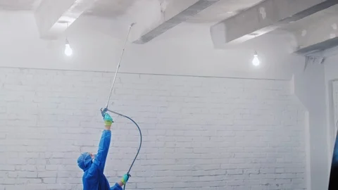 Worker painting the ceiling by airless spray gun with white color. Airless Spray Stock Footage 111858862