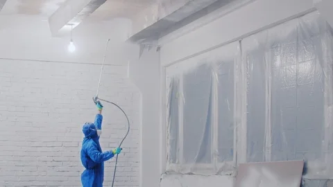 Worker painting the ceiling by airless spray gun with white color. Airless Spray Stock Footage 111860302