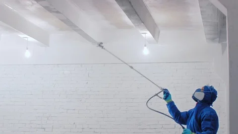 Worker painting the ceiling by airless spray gun with white color. Airless Spray Stock Footage 111860741
