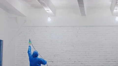 Worker painting the ceiling by airless spray gun with white color. Airless Spray Stock Footage 111865731