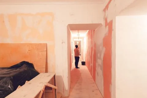 Worker is painting the ceiling by paint roller in corridor an apartment is inder Stock Photos