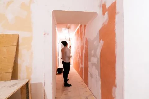 Worker is painting the ceiling by paint roller in corridor an apartment is inder Stock Photos