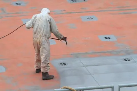 Worker painting ship hull using airbrush gray paint Stock Photos