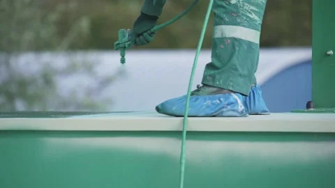 Worker is painting, using spray gun, applies coating composition to metal gre Stock Footage 149776110