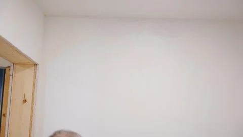 Worker painting wall with brush roller under the ceiling. Interior renovation Stock Footage 334062742