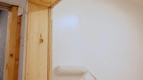 Worker painting wall with brush roller close to the door frame. Interior Stock Footage 334063046