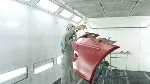 Worker paints bumper of car red using airless spray gun Stock Footage 163332359