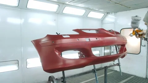 Worker paints car bumper red putting finishing coats in box Stock Footage 166576885