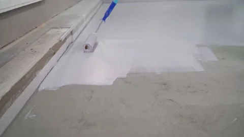 A worker paints the concrete floor with white paint. A worker paints the floor Stock Footage 143662259