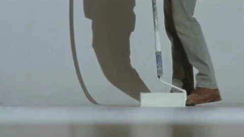 A worker paints a cyclorama white with a roller in a photo studio Video stock 337118695