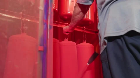 Worker paints fire extinguishers with spray gun at factory. Stock Footage 252038637