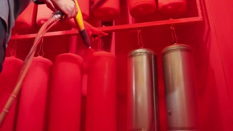 Worker paints fire extinguishers with spray gun at factory. Stock Footage 252038964