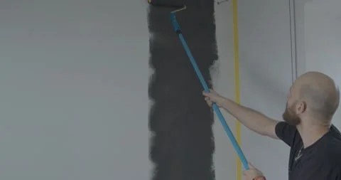 Worker paints wall in grey color moving roller up and down Stock Footage 170148405