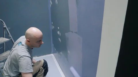 Worker paints walls using roller completing customer order Stock Footage 124003366