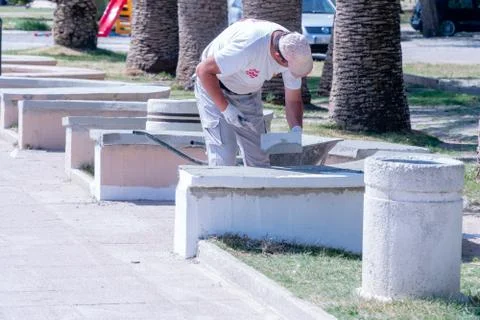 Worker paints a white bench Stock Photos