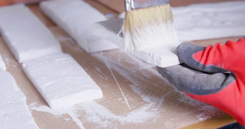 Worker paints white plaster brick cast at wooden table Stock Footage 170734546