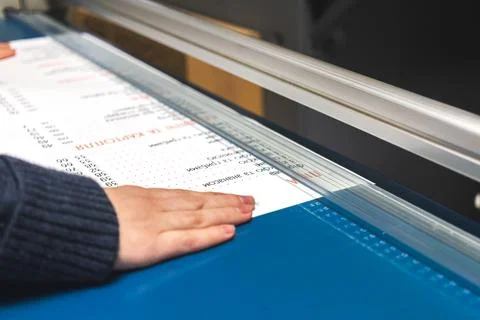 Worker with paper cutter machine in print house. Printing industry background Stock Photos