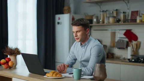 Worker passing online interview using webcam on laptop sitting at kitchen table Stock Footage 225651594