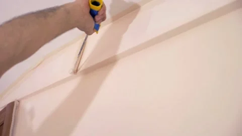 Worker passing the roller brush along ceiling frame to finishing work Stock Footage 132194210