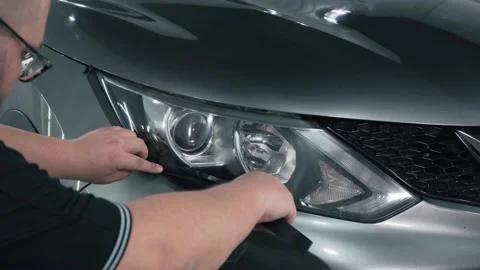 Worker pastes over headlamp optics with special tape around perimeter, prepares Stock Footage 141401516