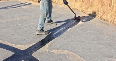 Worker patcher performs coating, crack sealing, bitumen emulsion road surface Stock Footage 257330207