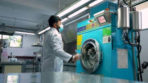 Worker Performing A Chemical Test On Textiles Using An Industrial Machine for Stock Footage 333963780