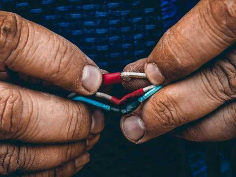 Worker performing electrical wiring, joining colorful cables using heat shrink Stockfoto's
