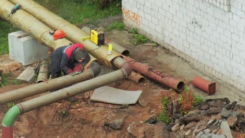 Worker performs arc welding operation on large diameter metal heating pipe, Видео 347580405