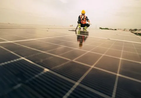 Worker performs maintenance on solar panels during overcast day in urban se.. Stock Photos