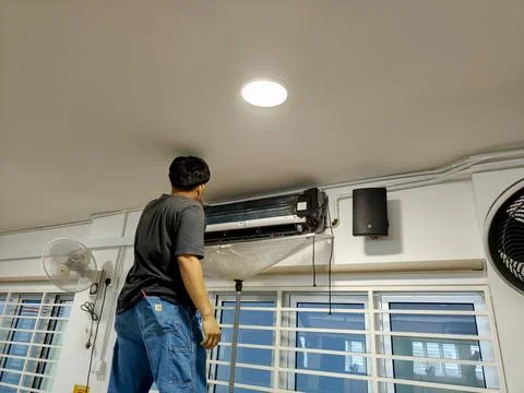 A worker performs maintenance on a split-system air conditioner Stock Photos
