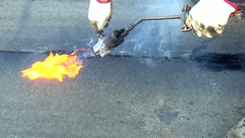 Worker performs sealing overlapping bitumen sheets on the flat roof of the bu Vidéo 87095288