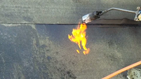 Worker performs sealing overlapping bitumen sheets on the flat roof of the bu Stock-Footage 87095374
