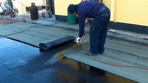 Worker performs sealing overlapping bitumen sheets on the flat roof of the bu 스톡 동영상 99605445